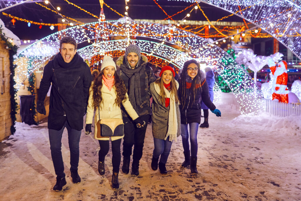 A group of friends have fun walking on Christmas streets at night.