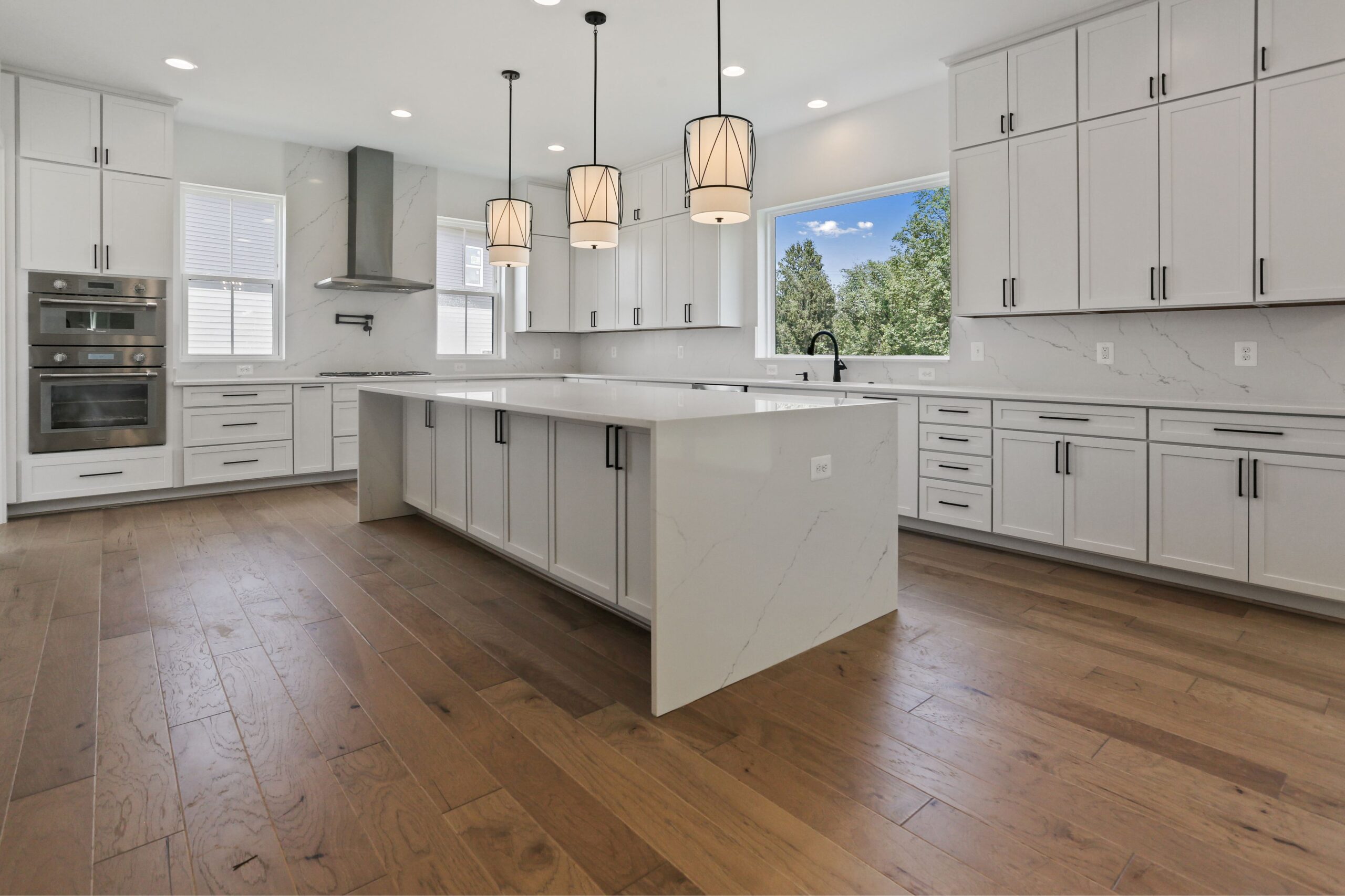 Spacious kitchen with a wealth of sleek white cabinetry and large center island.